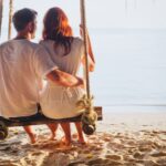 couple assis sur une balançoire face à la mer lors d'un séjour romantique