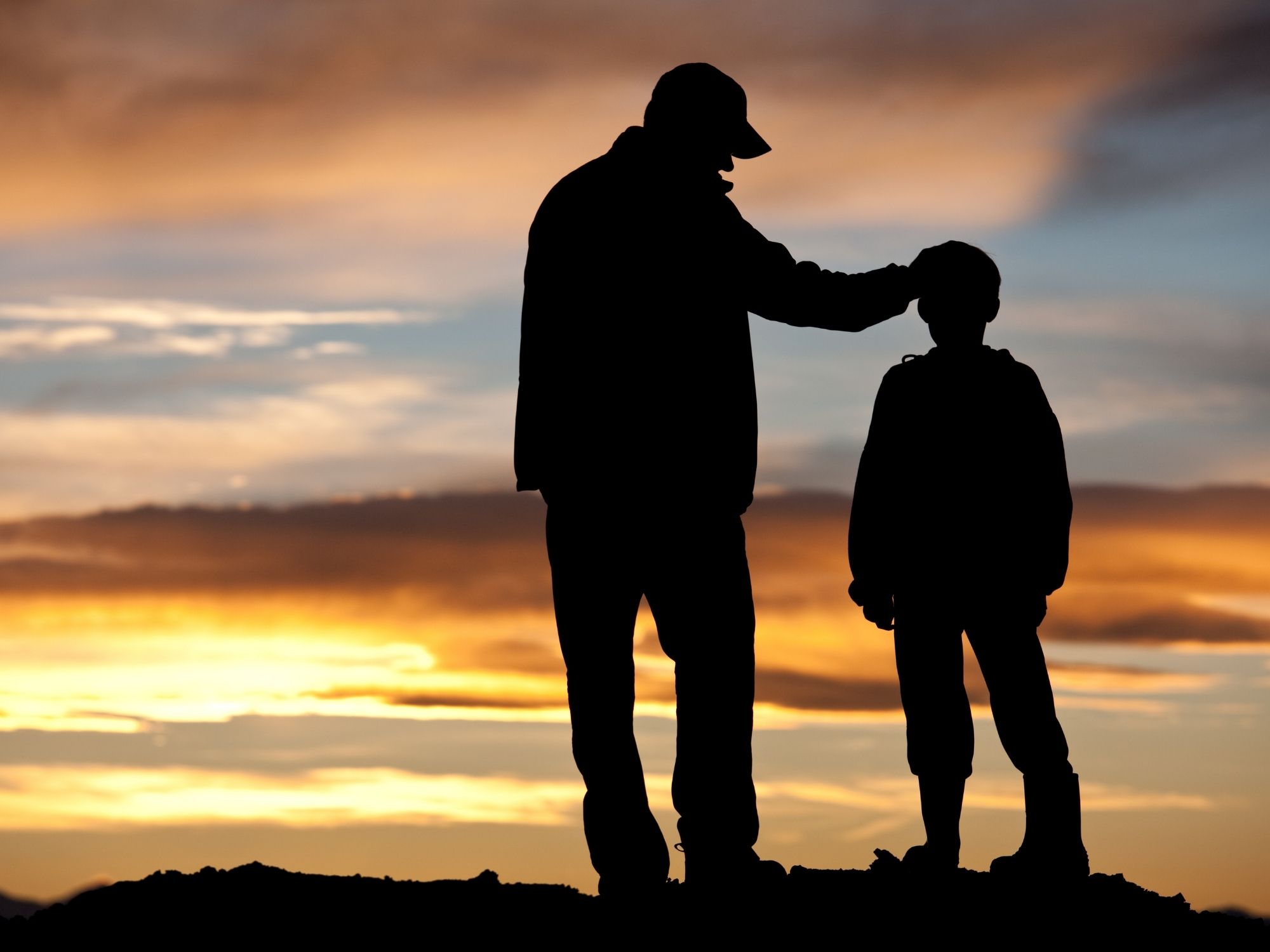 silhouette d'un adulte et d'un enfant au coucher du soleil